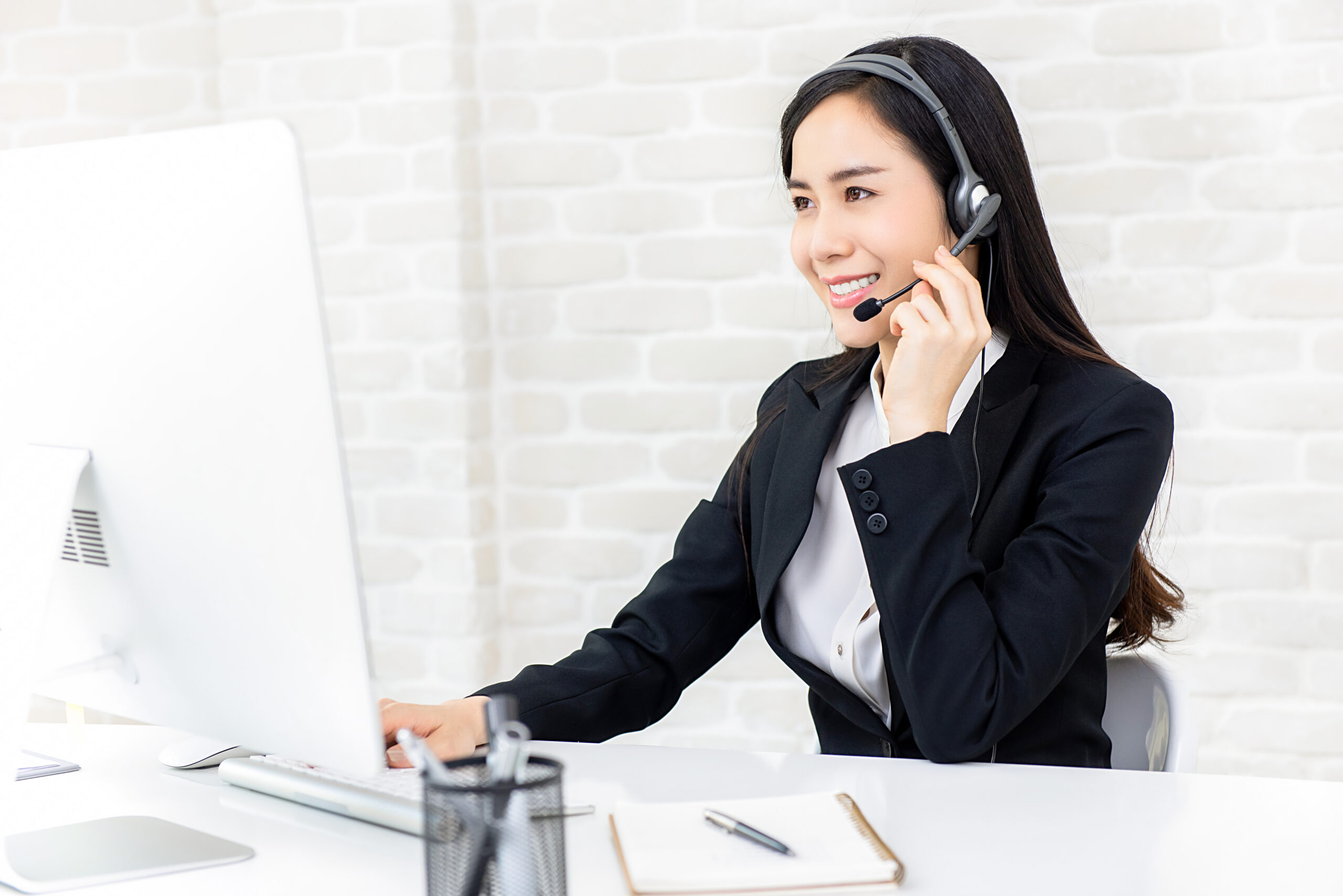 Young beautiful Asian businesswoman wearing headphone working in call center office as a customer service operator