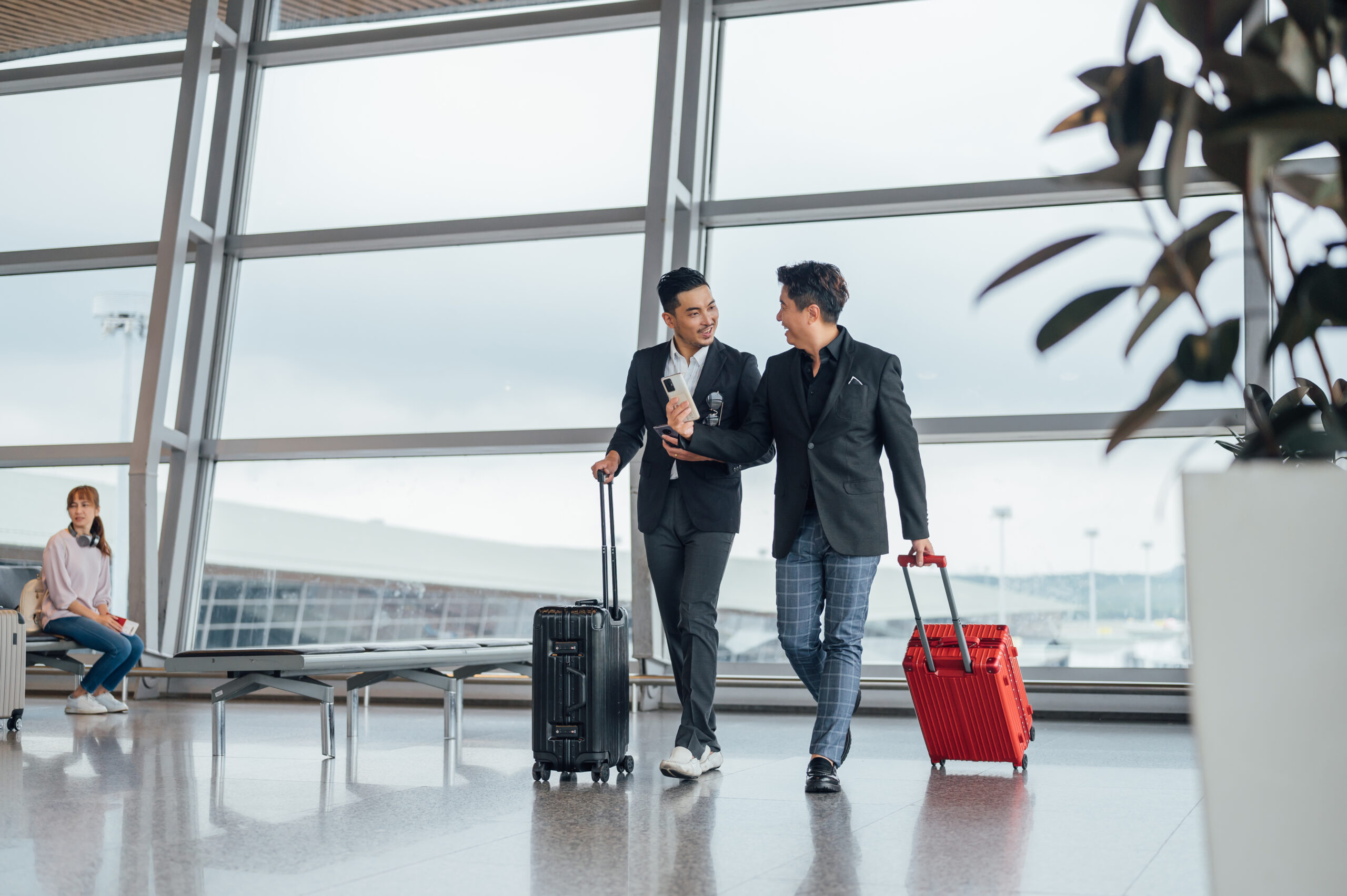 Shot of two Asian Chinese businessman walking with luggage inside airport terminal.